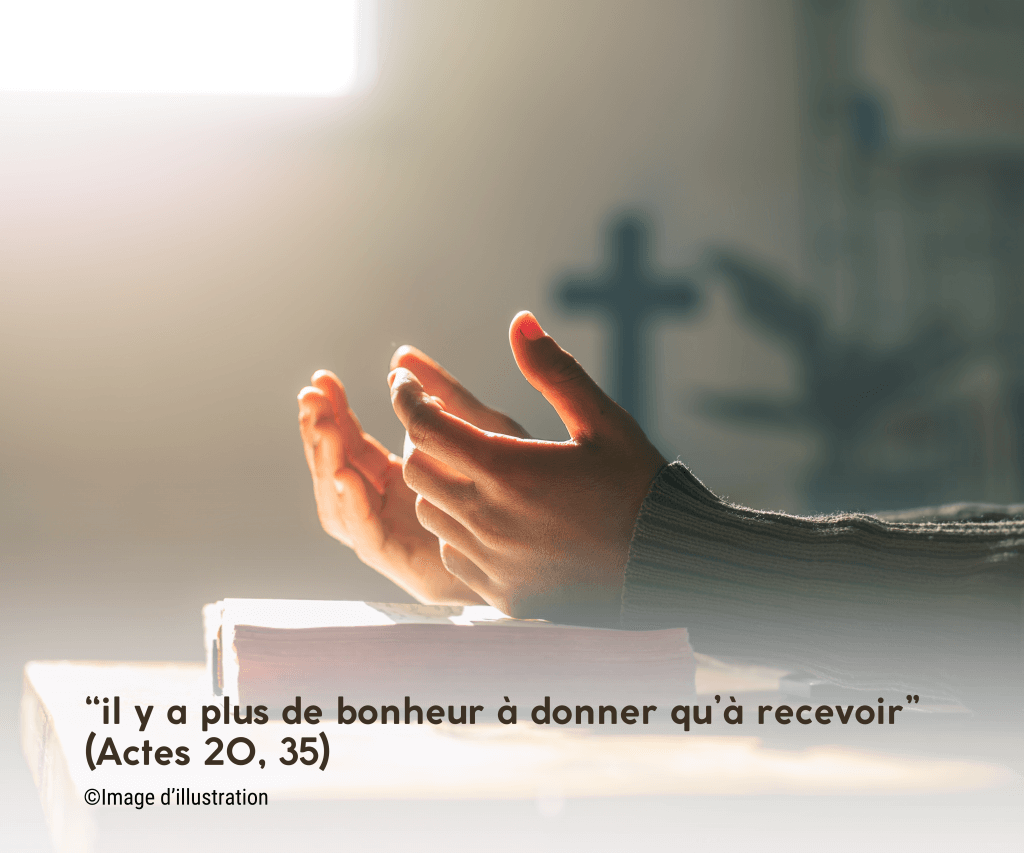 Bible ouverte avec une croix et des mains en prière, représentant la foi chrétienne et le don.